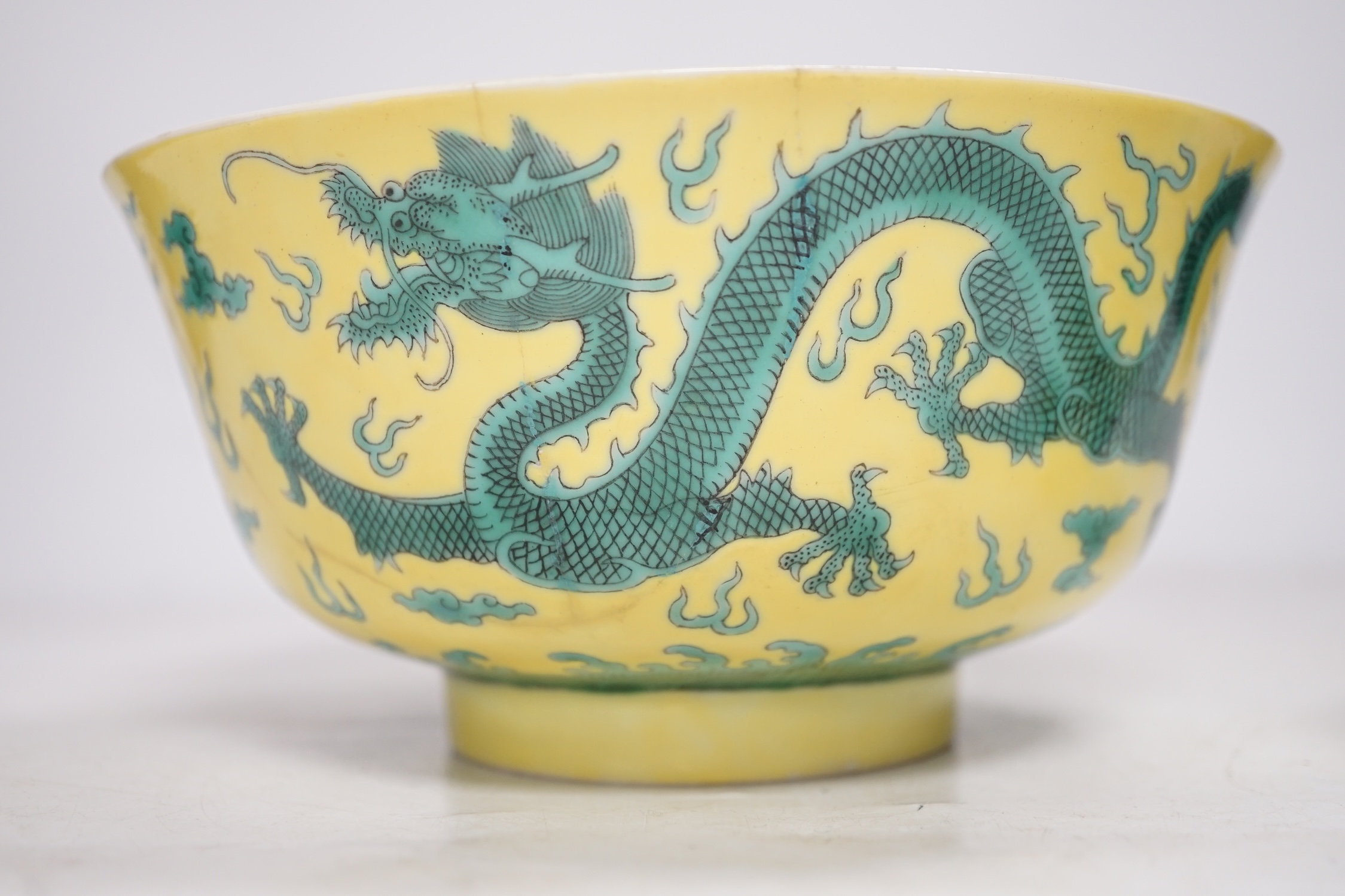 A Chinese yellow ground 'dragon' bowl, probably late Qing dynasty, and a similar floral cup, bowl 9cm high, 18.5cm diameter. Condition - bowl has a large section restored